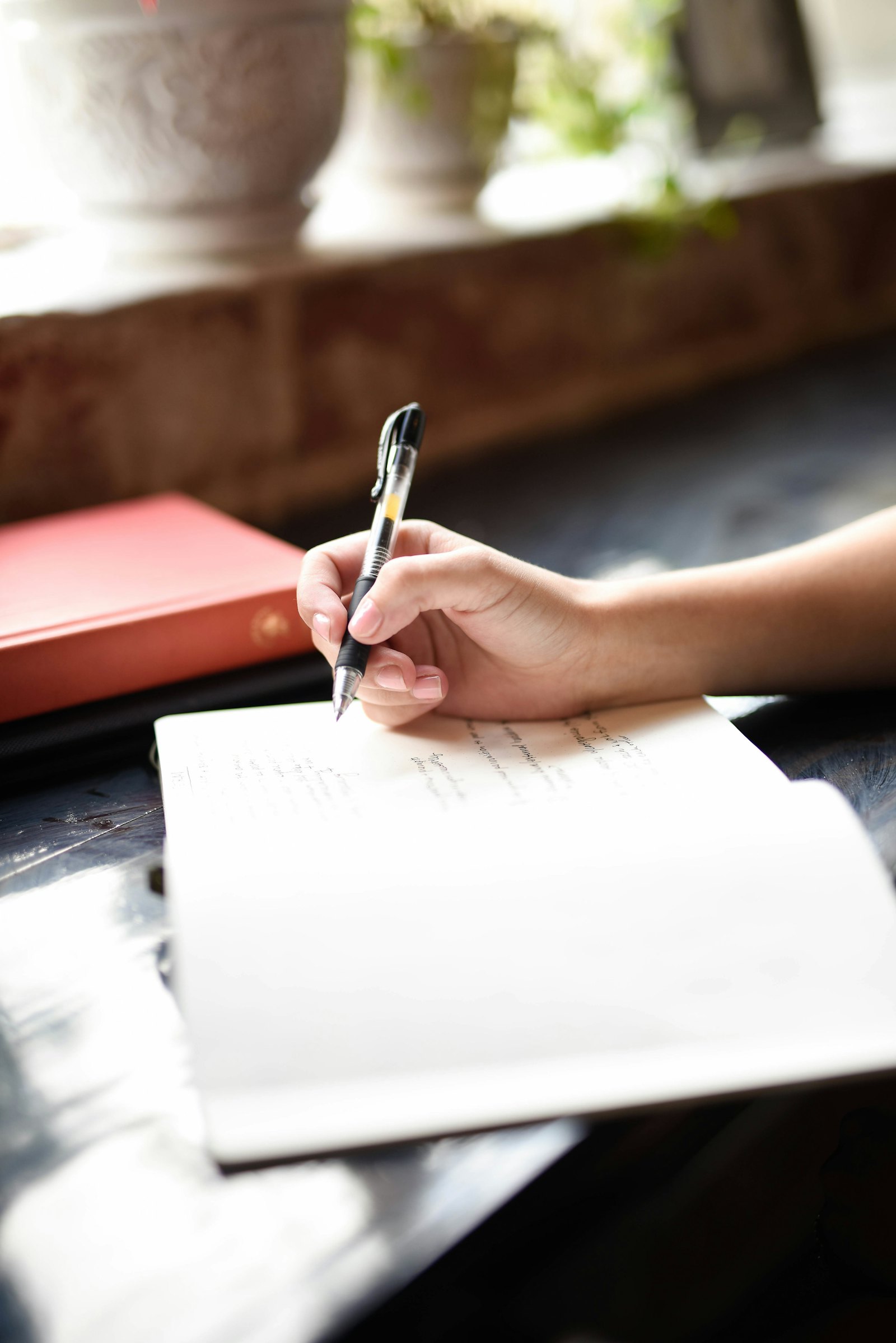 Hands writing in a notebook with a pen